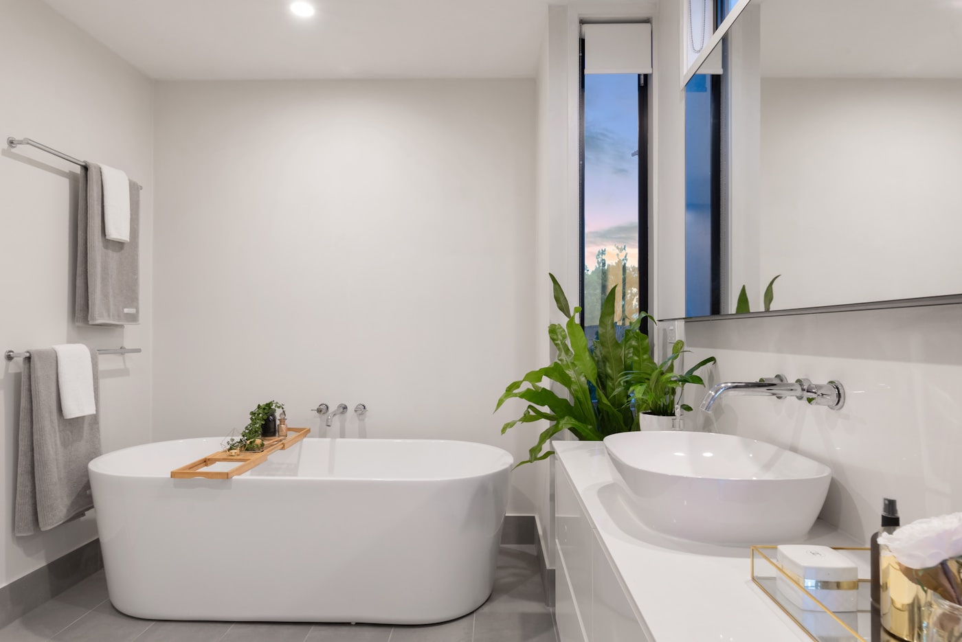 Bathing room with a freestanding tub and a single plant beside the window