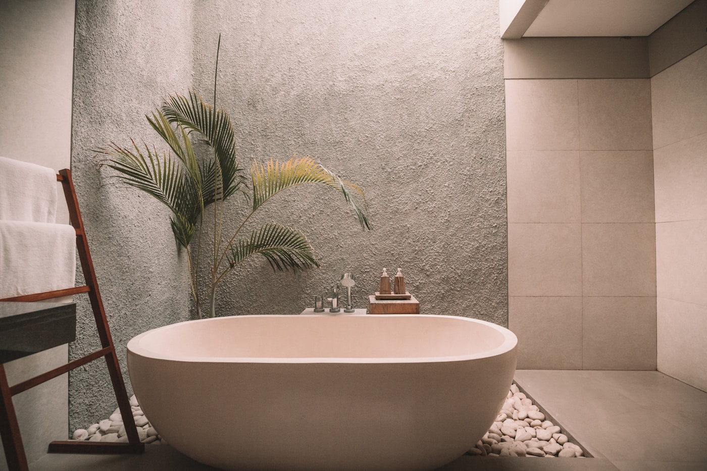 The bathing floor — a freestanding stone tub against a textured stone wall with a palm