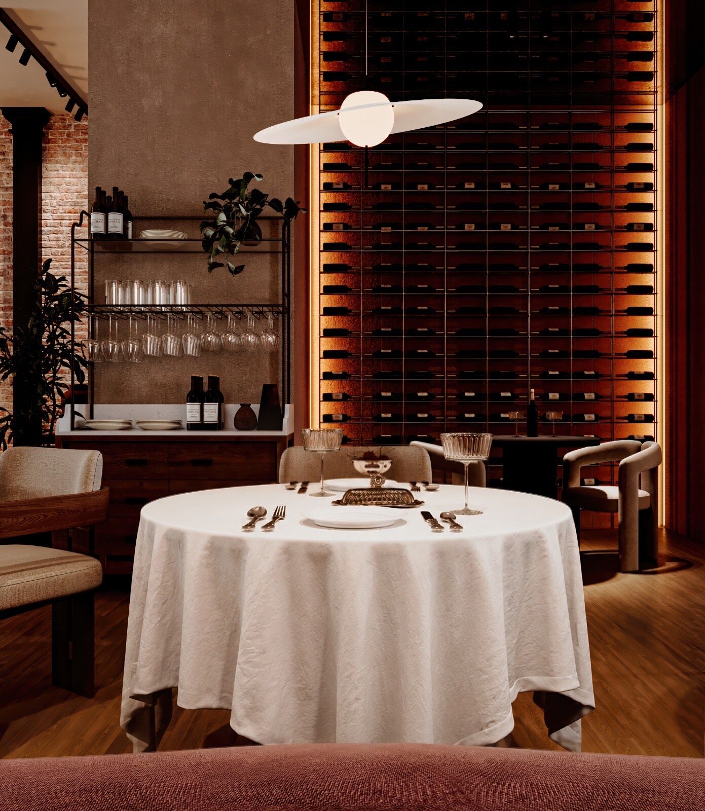 A round table dressed in white linen in front of the full-height backlit wine wall