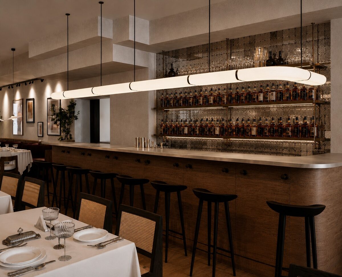 The back bar — bottles ranged on lit shelves beneath a long linear pendant