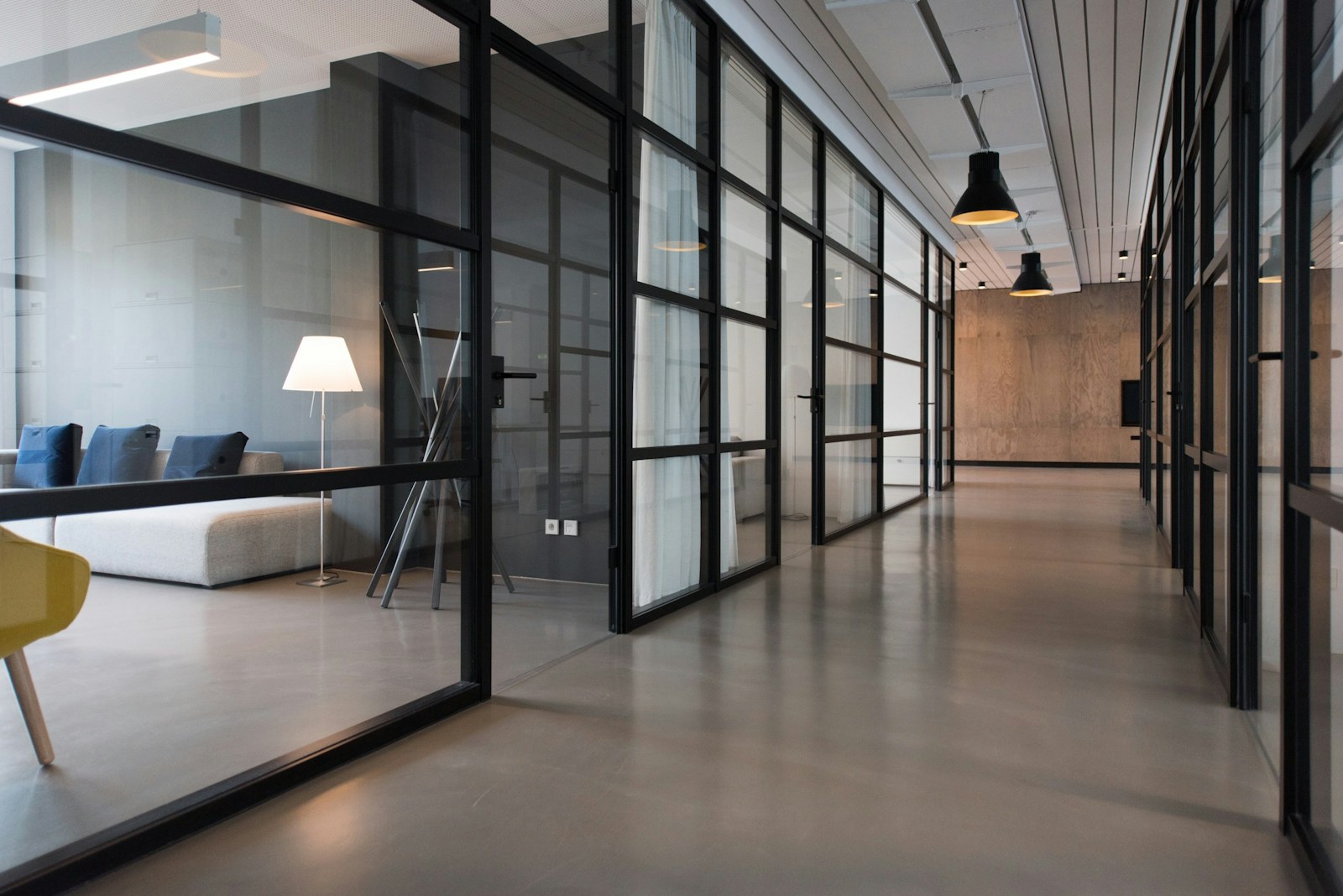 The studio’s workspace behind steel-framed glass partitions, lit softly in the evening
