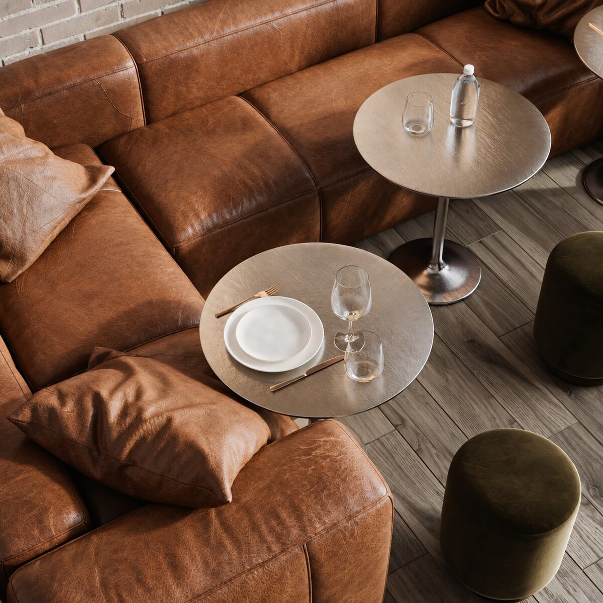 Close detail of the leather seating, a round table set for two, and an olive pouf